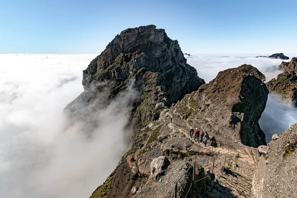 Hikers on a rugged Pico Ruivo ridge trail above the clouds